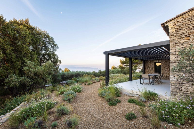 Installation d'une pergolas bioclimatique à lames orientables noir texturé en aluminium TECHNAL pour la terrasse d'une maison en pierre à Belcodène