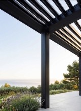 Installation d'une pergolas bioclimatique à lames orientables noir texturé en aluminium TECHNAL pour la terrasse d'une maison en pierre à Belcodène